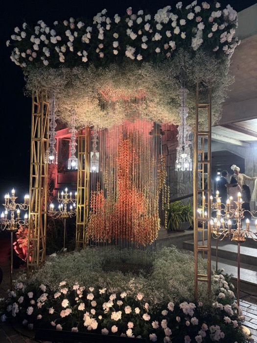 Night mandap of white roses and baby's breath with a curtain of hanging golden bells and crystal candelabras — Panigrahana decor