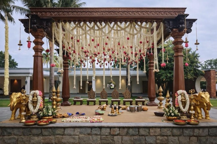 Carved wooden mandap with jasmine string canopy, pink poms and golden elephants — Panigrahana decor