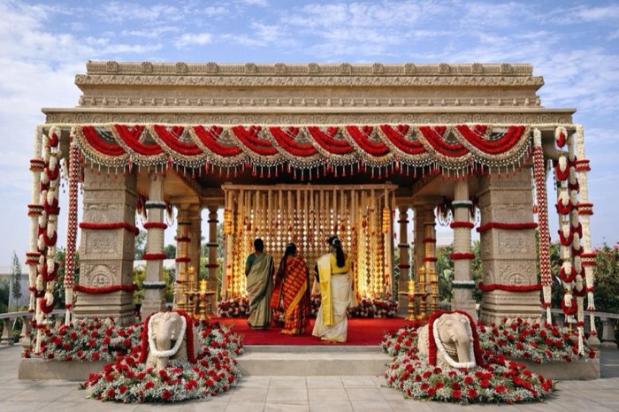 Carved temple mandap dressed in red rose and jasmine garland swags with stone elephants — Panigrahana decor