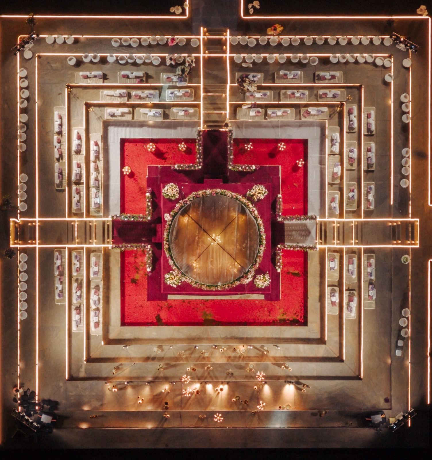 Aerial view of a red and gold mandap inside concentric lit stages, Panigrahana in-house decor