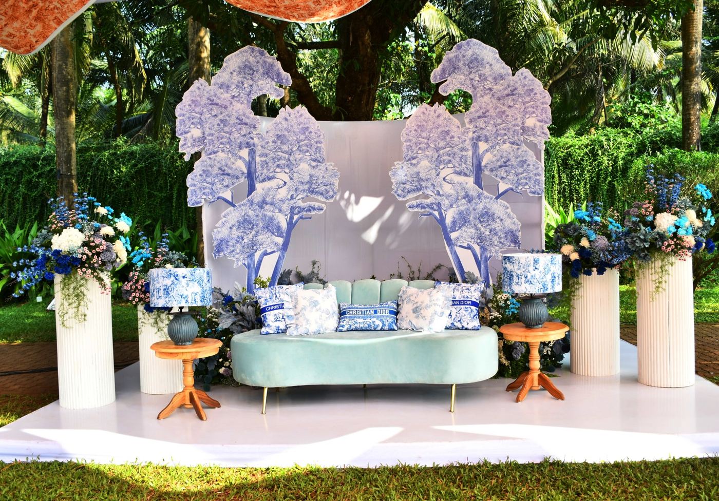 Chinoiserie-print stage backdrop with mint sofa and blue floral styling, styled by Panigrahana