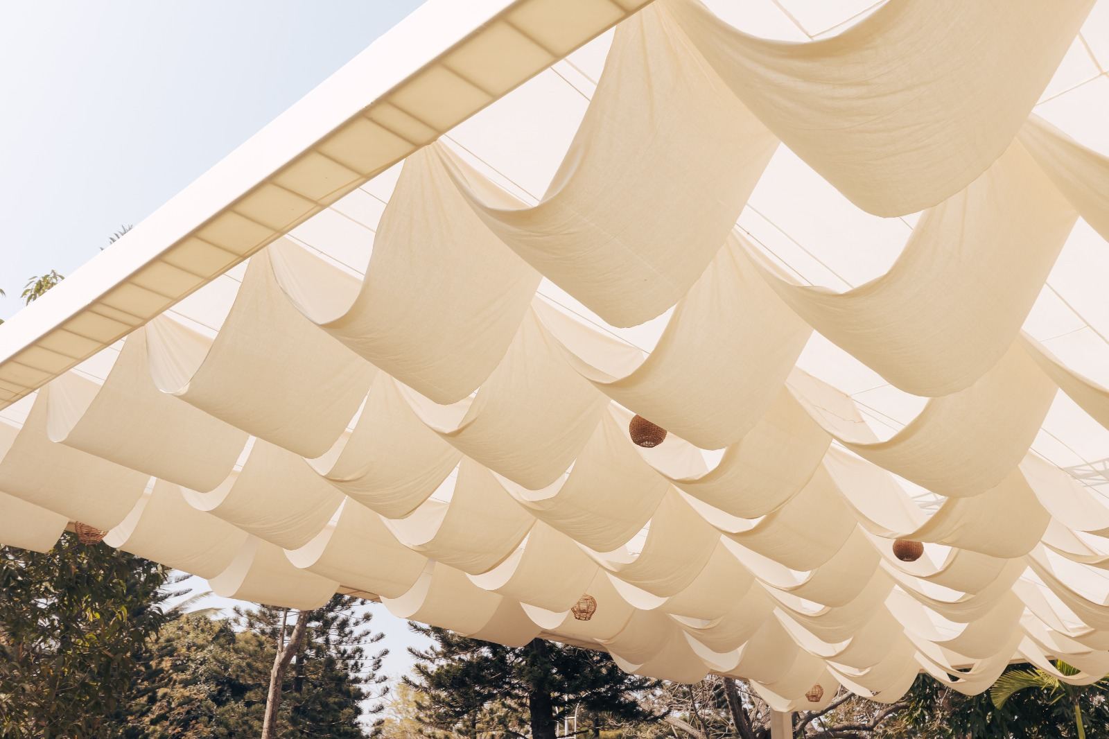Ivory draped fabric canopy ceiling rigged over an outdoor celebration