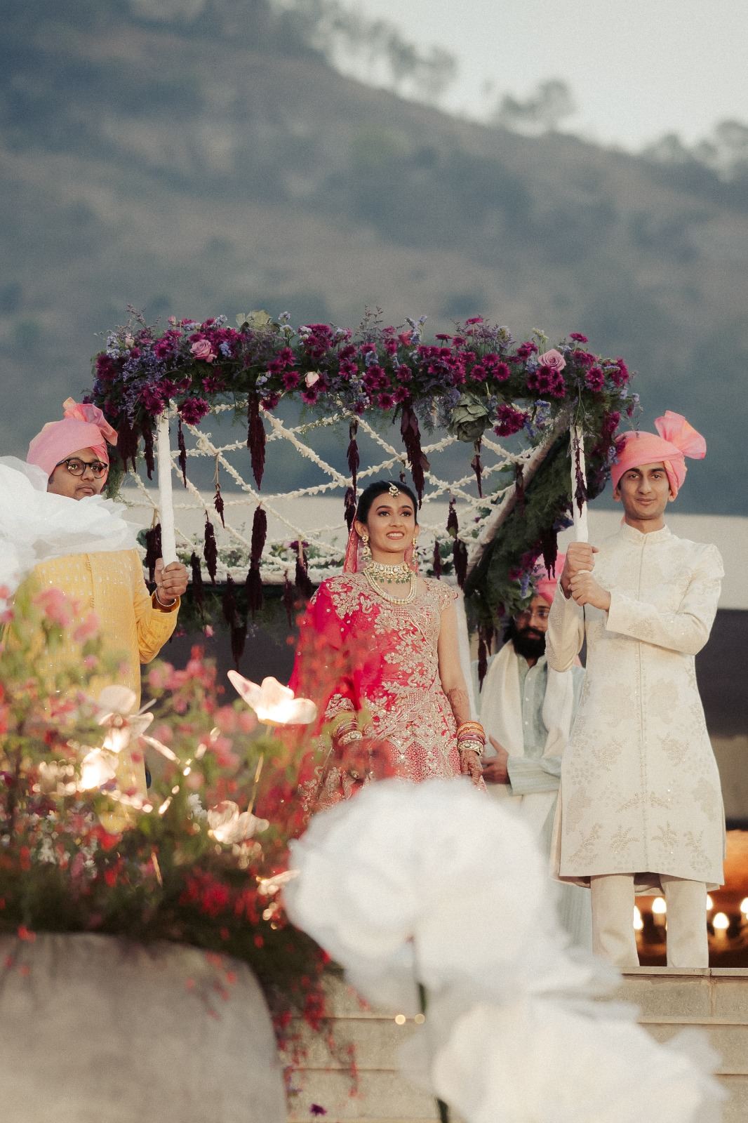 Couple framed by a pink floral palki-style swing installation