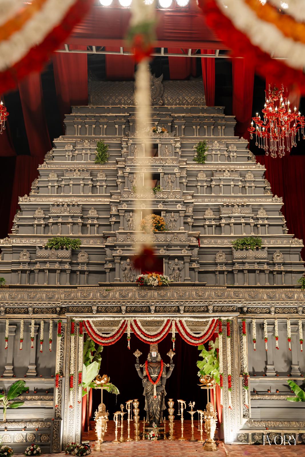 Full-height gopuram replica stage with red drapes and marigold accents