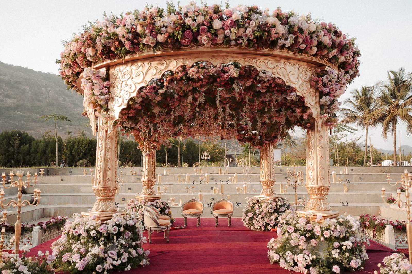 Grand pastel floral mandap centred in a stepped outdoor amphitheatre, designed by Panigrahana
