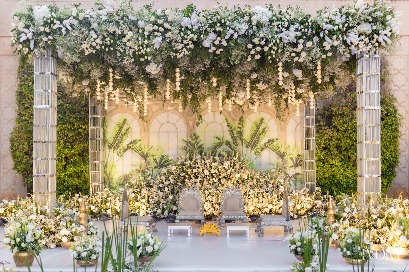 Ivory arch reception stage with white florals and rows of green seating