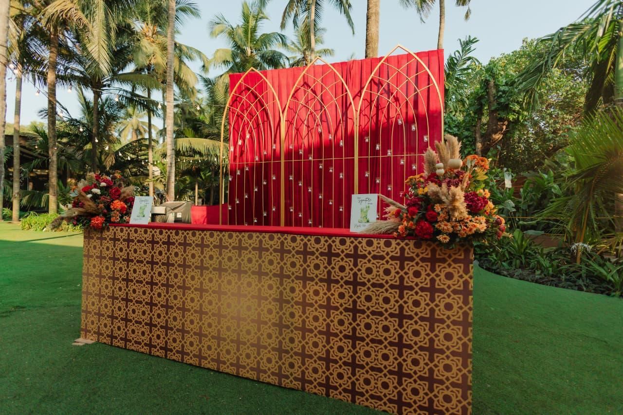 Gold jaali-pattern bar counter with floral arrangements on a lawn