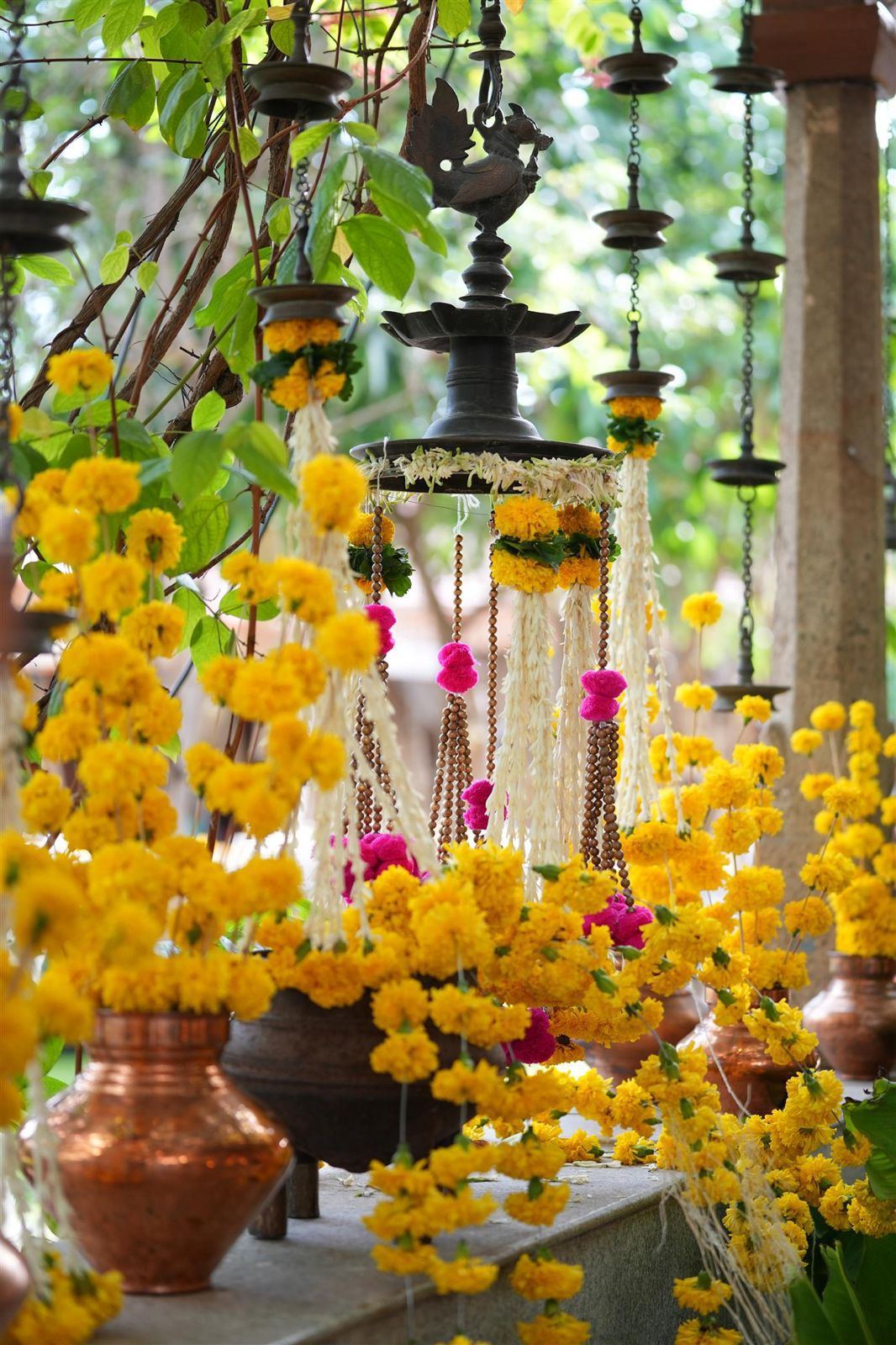 Marigold strings, hanging brass lamps and copper kalash at an entrance