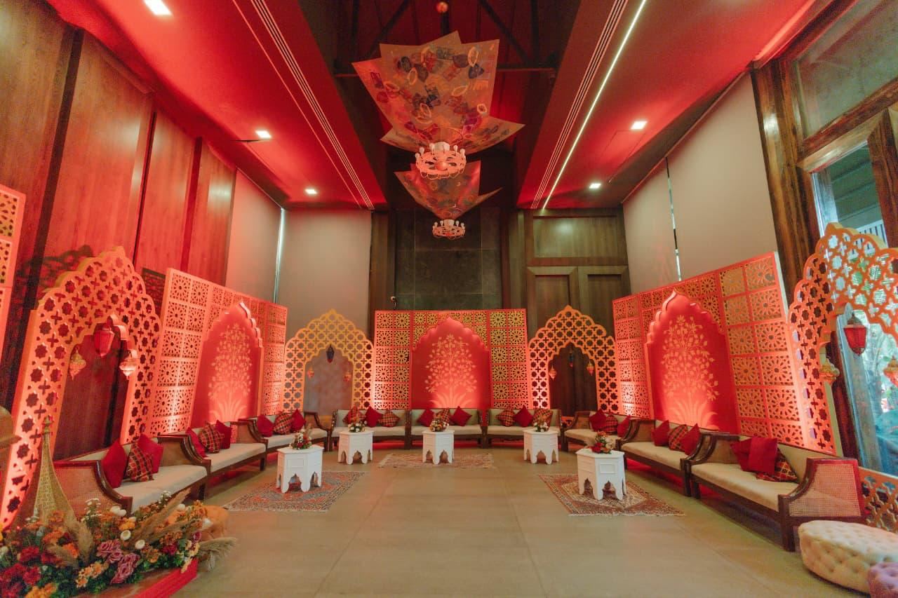 Red draped mehfil hall with arched panels and low seating
