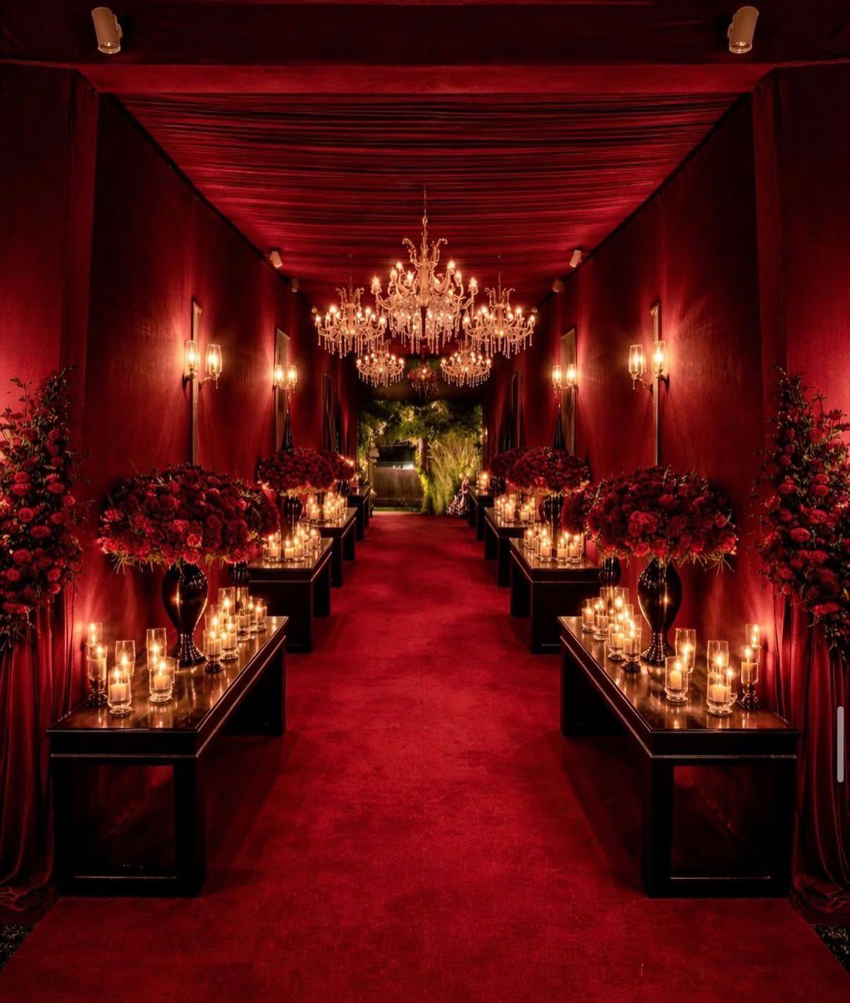 Red velvet draped corridor lined with chandeliers, candles and roses