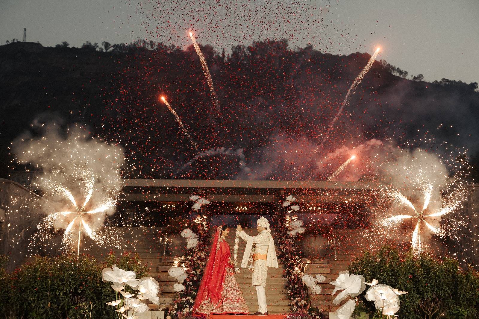 Varmala moment framed by fireworks and spinning ground pyrotechnics