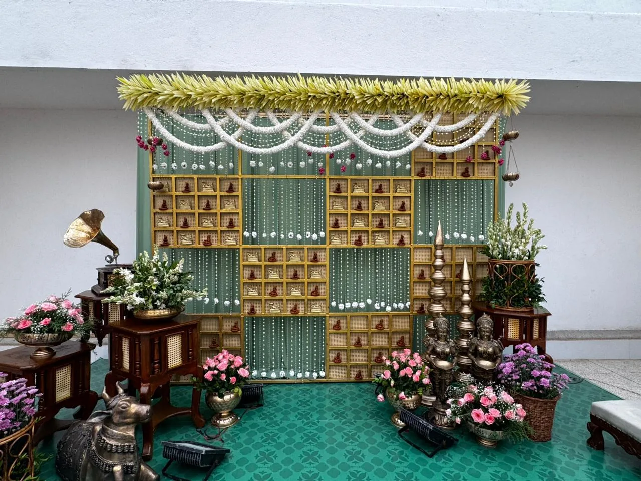Green and gold ceremony backdrop with brass lamps at Moongate