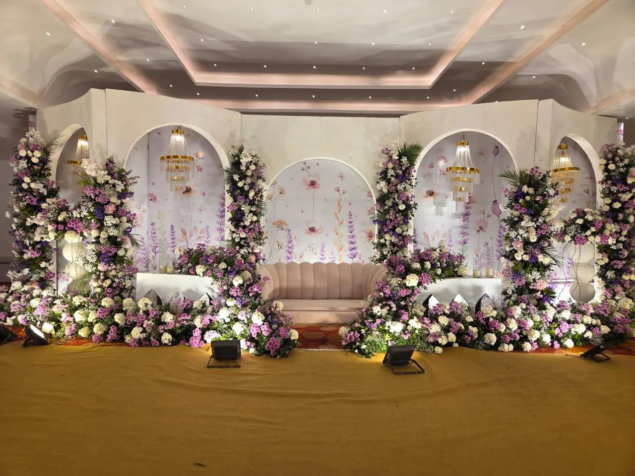 White arched stage with purple flowers at Moongate