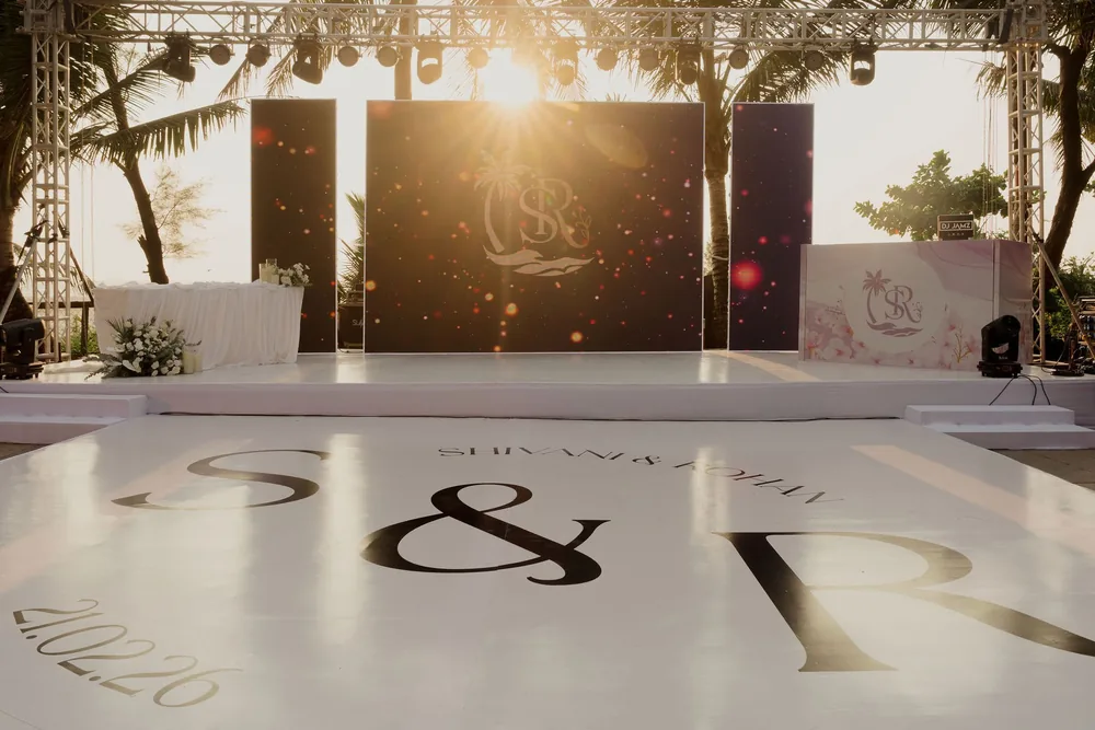 White reception dance floor at Beleza by the Beach, Goa printed with large S & R initials, in front of a stage with monogram screens.