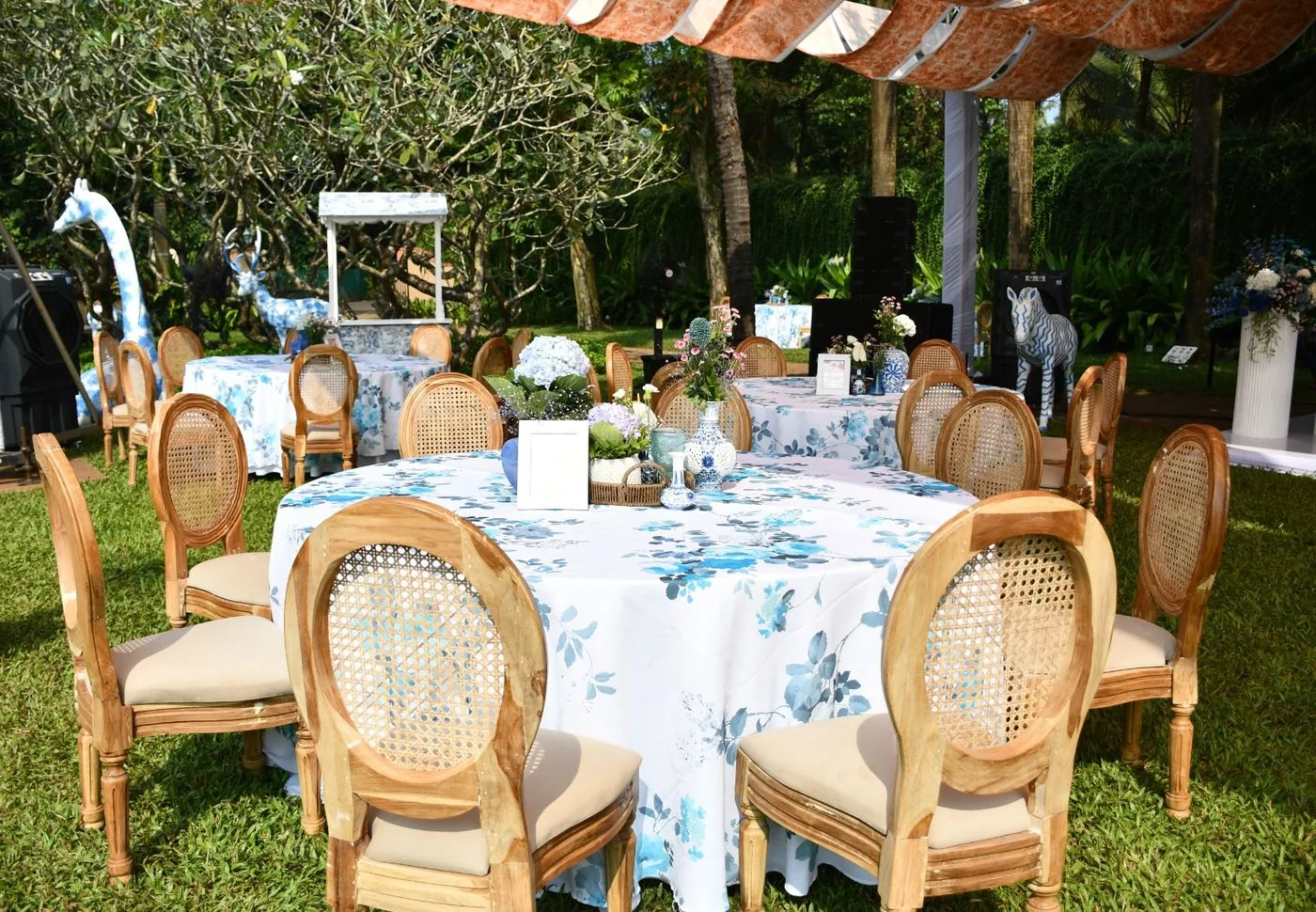 Blue and white garden tables with floral arrangements and cane chairs