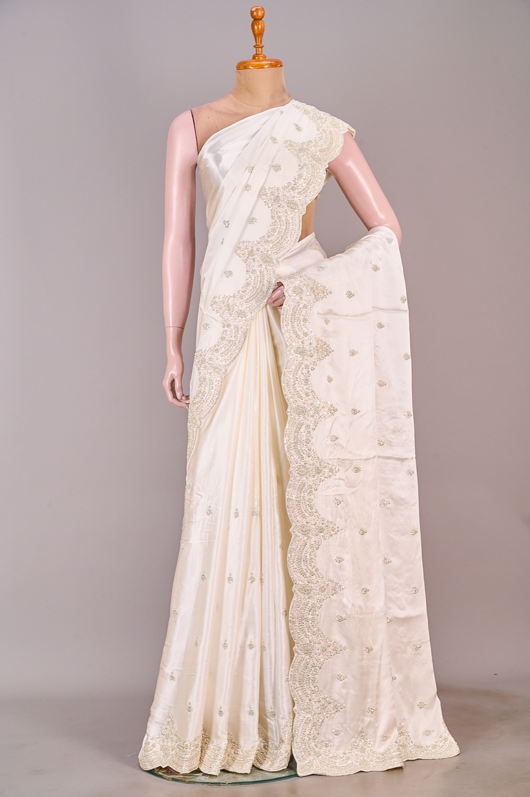 White silk satin saree with silver embroidery on the border and pallu, shown on a mannequin