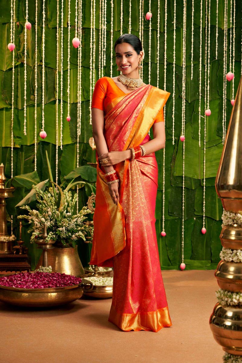 Pink Kanchipuram silk saree with parrot and vine brocade and a gold border, worn by a model