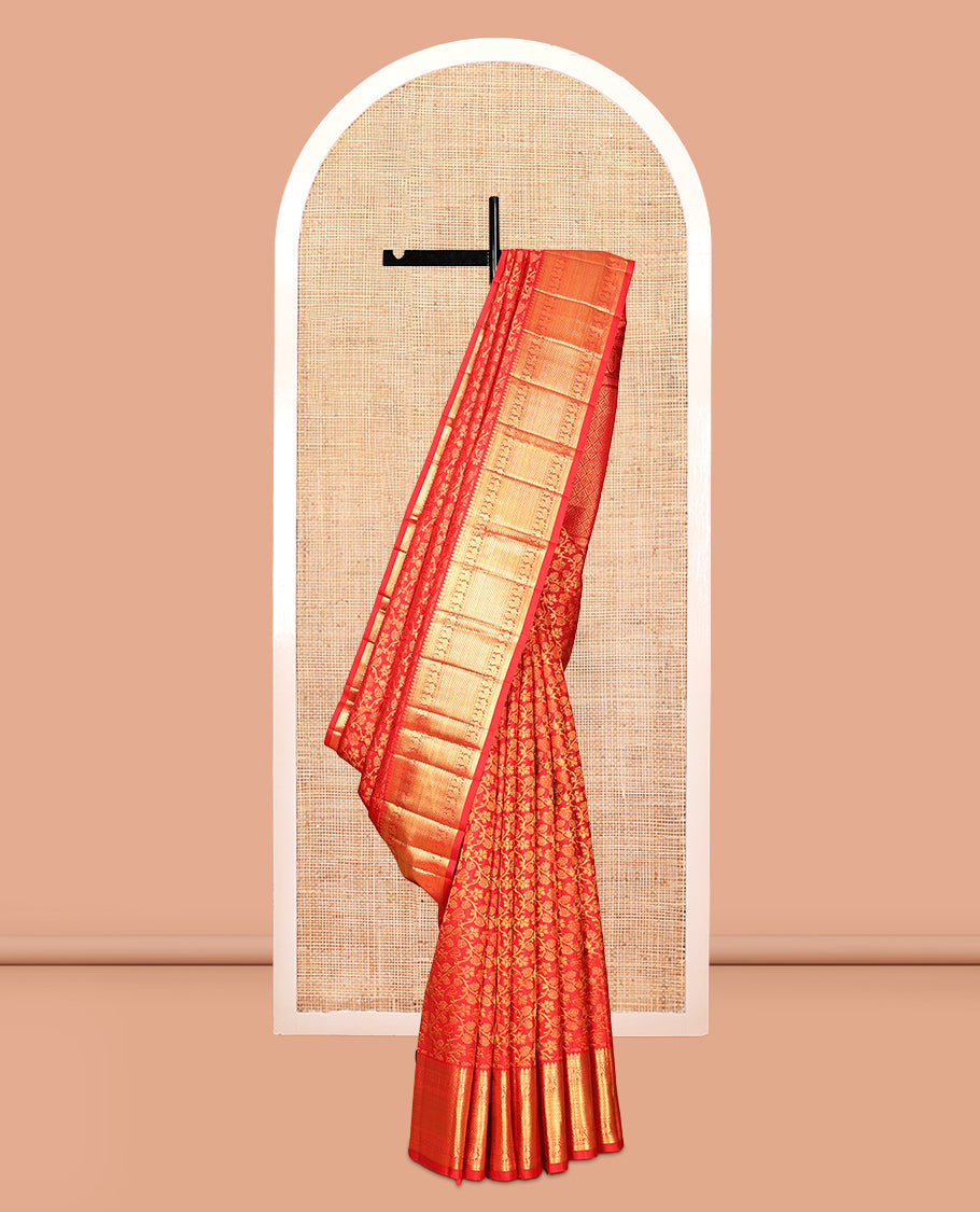 Red Kanchipuram wedding silk saree with a gold zari border, draped on a display stand
