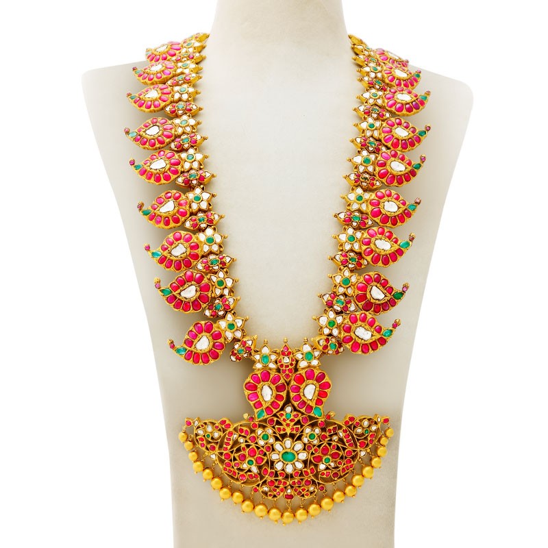 Antique gold mango haram with red, green and white stones and a gold-bead fringe, on a display bust