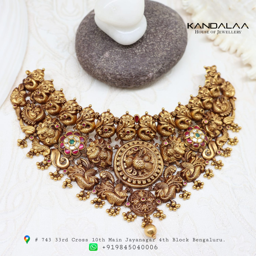 Antique gold temple choker with peacock motifs and a central medallion, shown with the jeweller's logo and address
