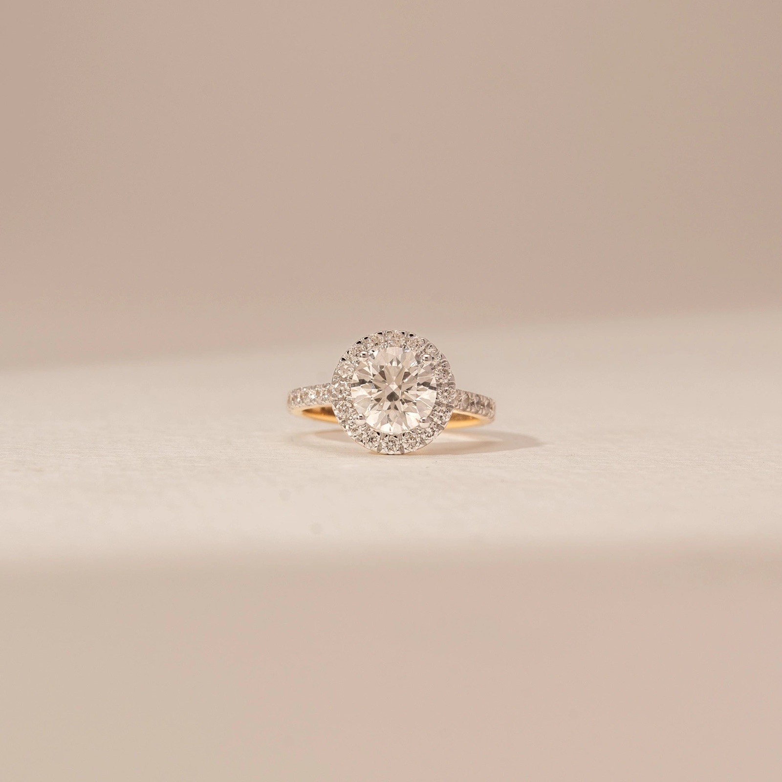 Round lab-grown diamond halo engagement ring with a white-gold head on a yellow-gold band
