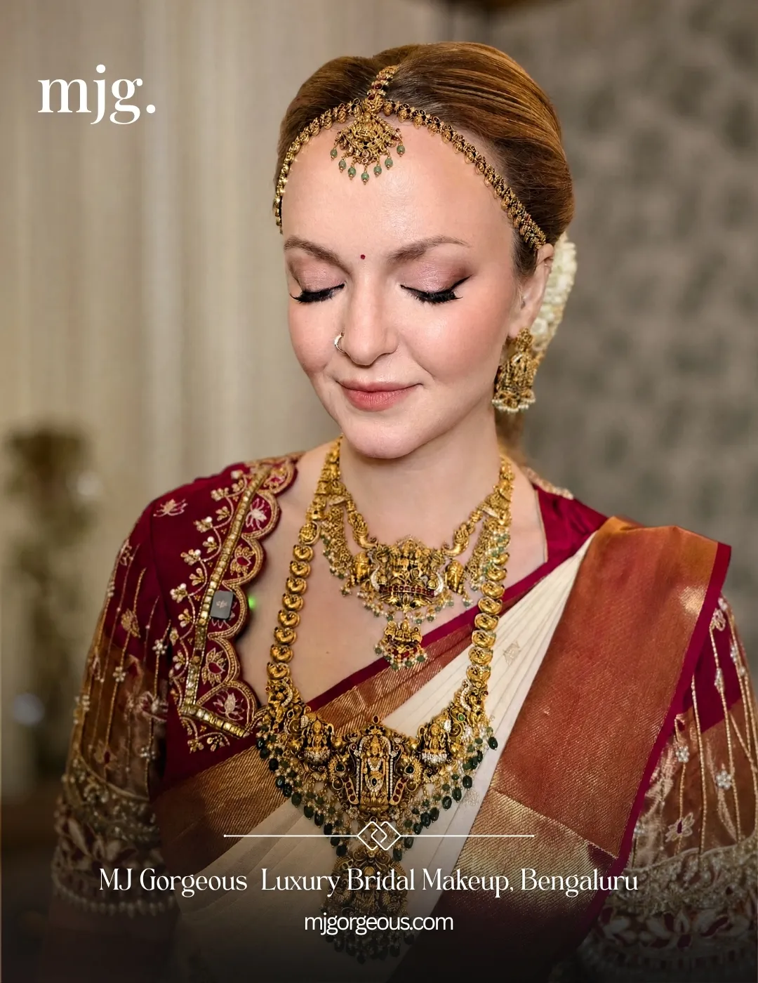 South Indian bride in a red and cream silk saree with temple jewellery, a maang tikka and jasmine in her hair