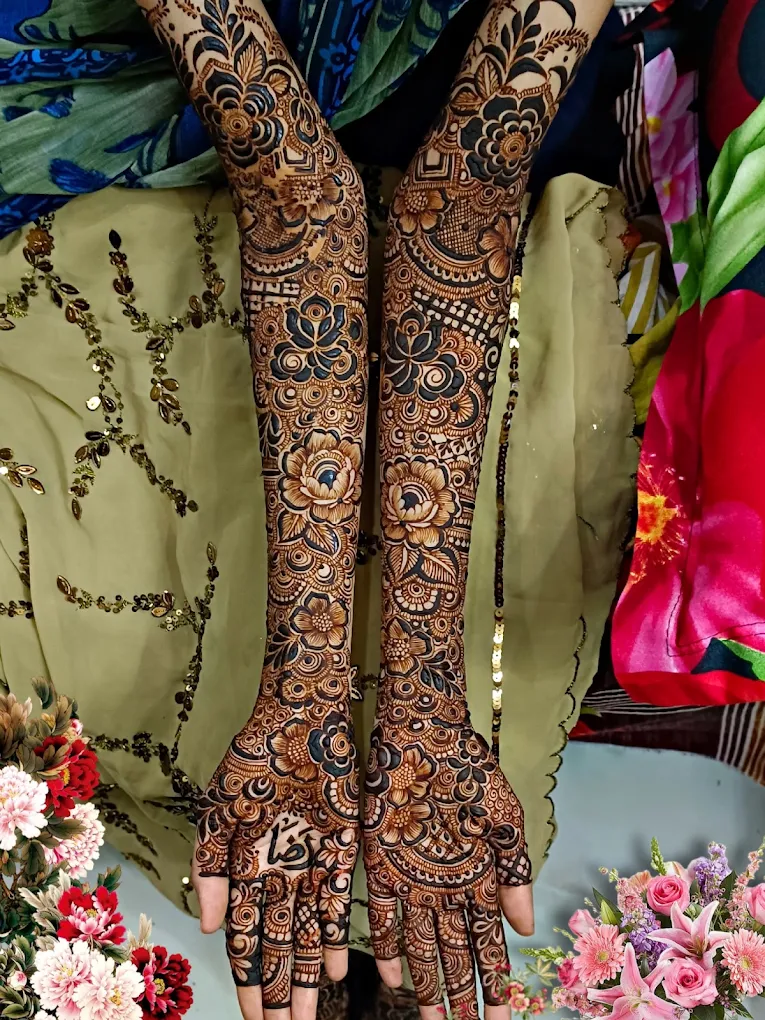 Bridal mehendi on the backs of both hands and arms to the elbow, with large roses, leaves and lattice bands