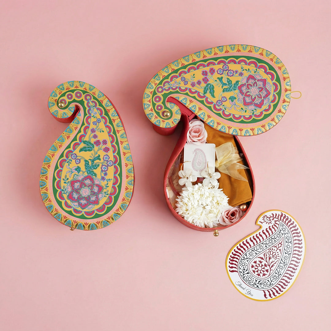 Paisley-shaped thamboolam box holding a gajra, bangles, blouse fabric and a thank-you card