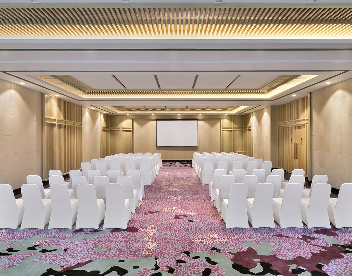 Silver Oak banquet hall at Coorg Marriott set theatre-style with white chairs either side of a central aisle, facing a projection screen