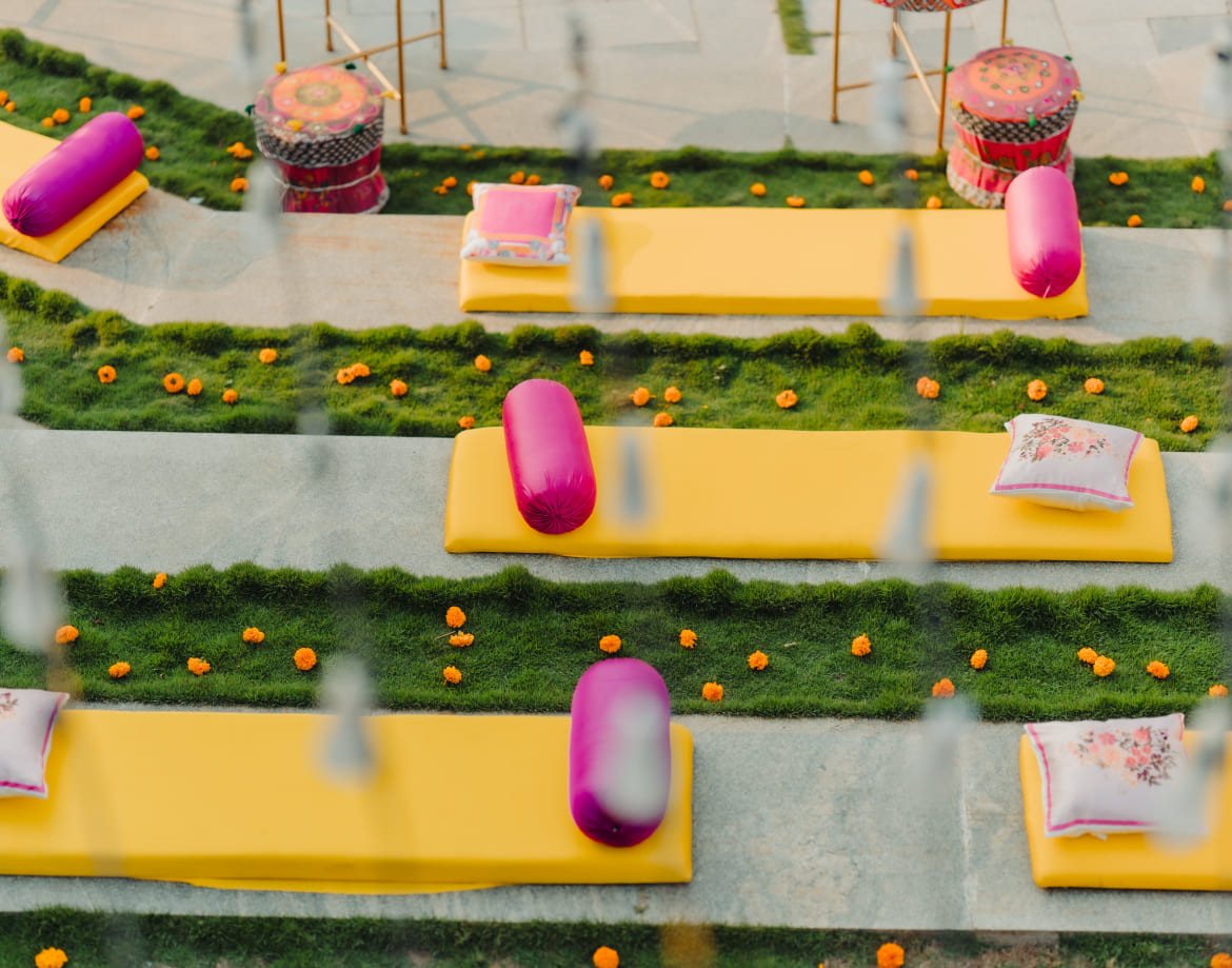 Close view of the stepped seating at Coorg Marriott laid with yellow mattresses, pink bolsters and marigold heads along turf risers