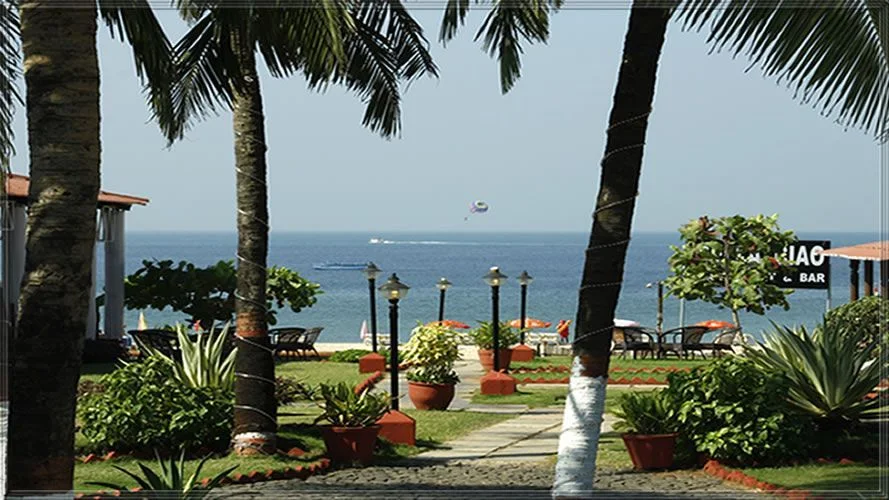 Pool, garden lawn and beach bar at dusk with the Arabian Sea behind at La Calypso, Candolim, North Goa — Panigrahana