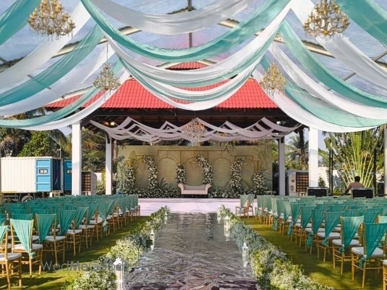 Ceremony set-up at Mandara — a green and white draped ceiling over the aisle leading to a floral mandap built under the pagoda-roof pavilion, chairs in rows on the grass