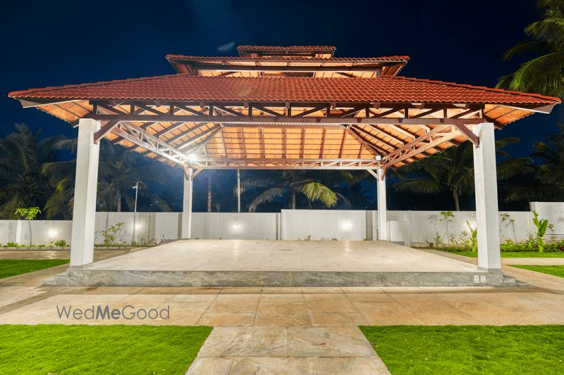 The pagoda pavilion at Mandara at night, undressed — a twin-pitched tiled roof on timber posts over a raised stone platform, uplit from the lawn