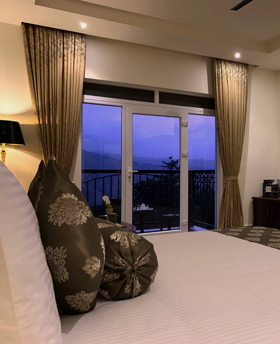 Suite at Montrose Golf Resort at dusk, bed in the foreground and the balcony doors open on a deep blue sky over the hills