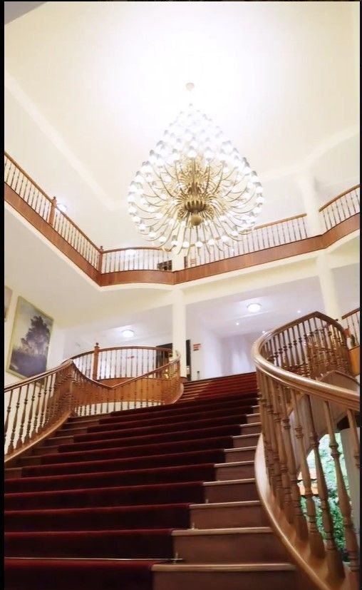 The balustraded timber staircase in the main block at Montrose Golf Resort, rising under a starburst chandelier to a white galleried landing