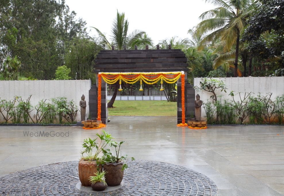 The stone entrance gateway at Royalton Leisure, hung with marigold garlands and flanked by seated stone figures on a paved forecourt