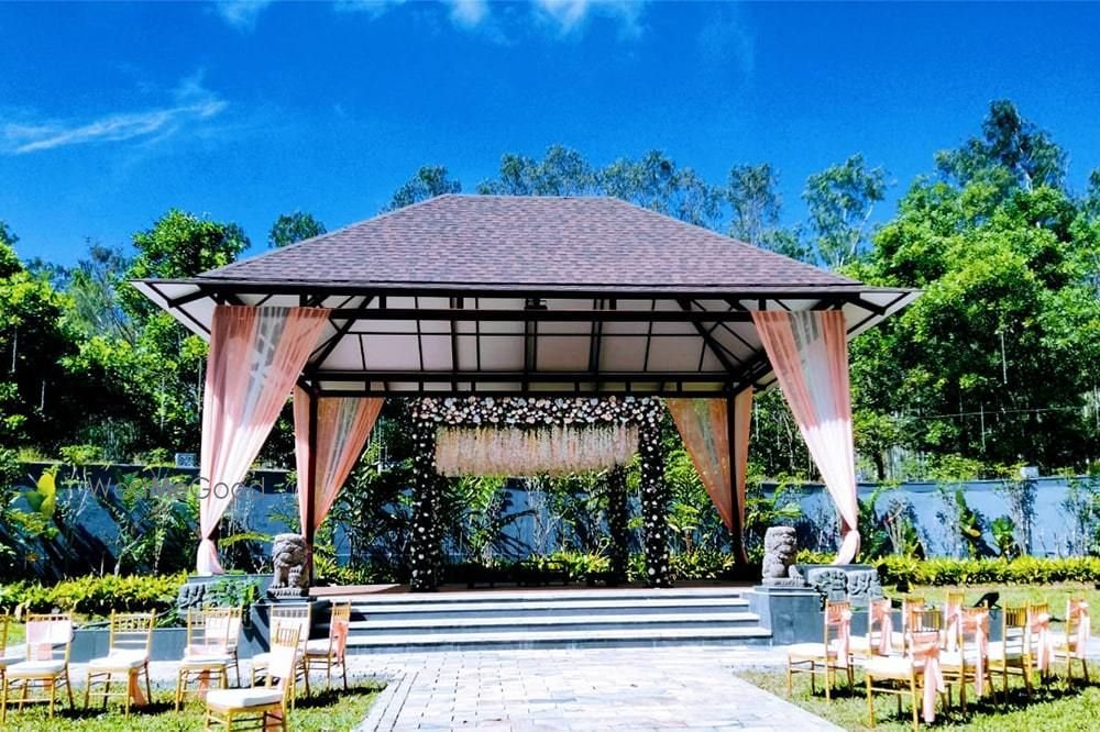 The open-sided pavilion at Royalton Leisure with a pitched roof, blush drapes and a floral backdrop above stepped access from the lawn