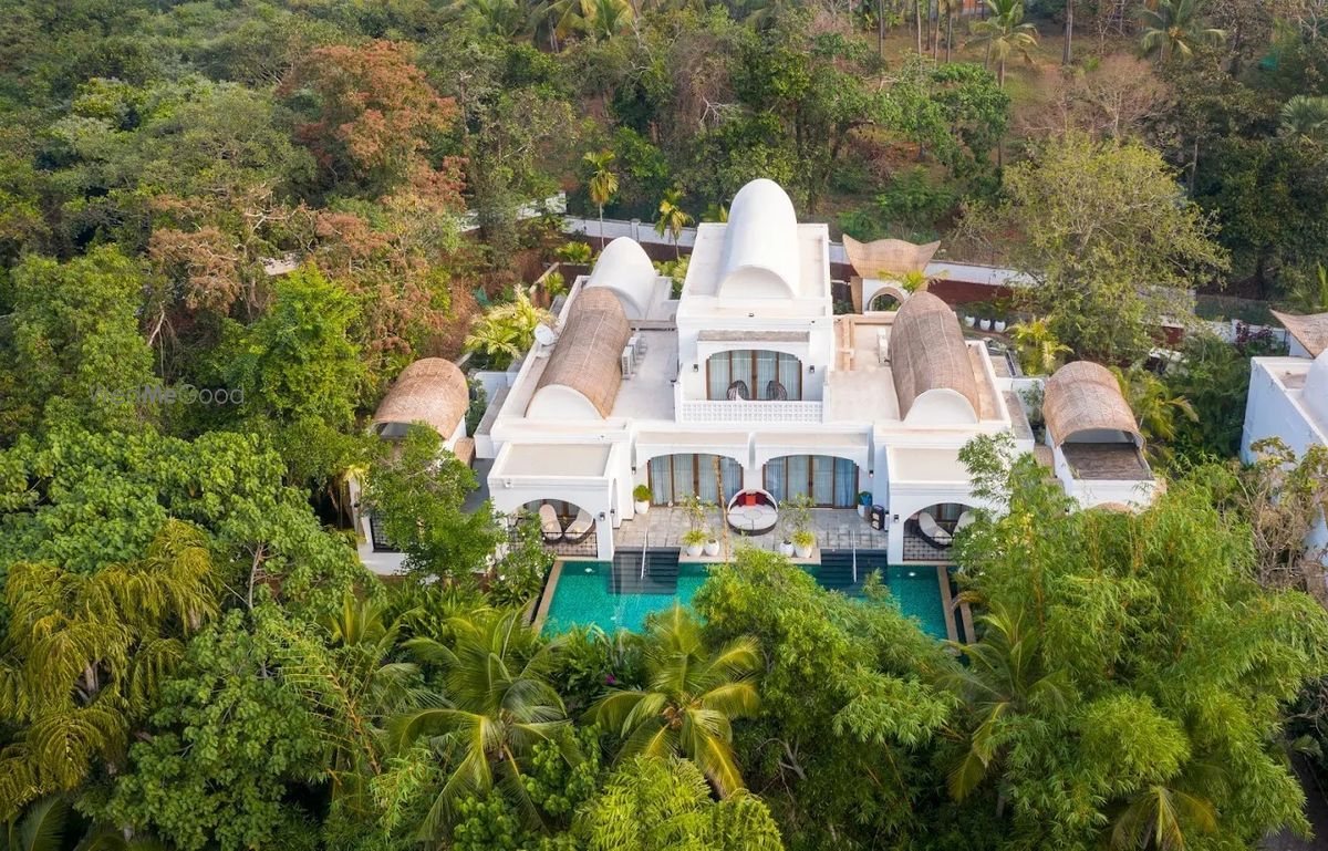 Aerial view of a villa cluster at Taj Bekal set into the palm canopy, its pool and terrace visible between the curved roofs
