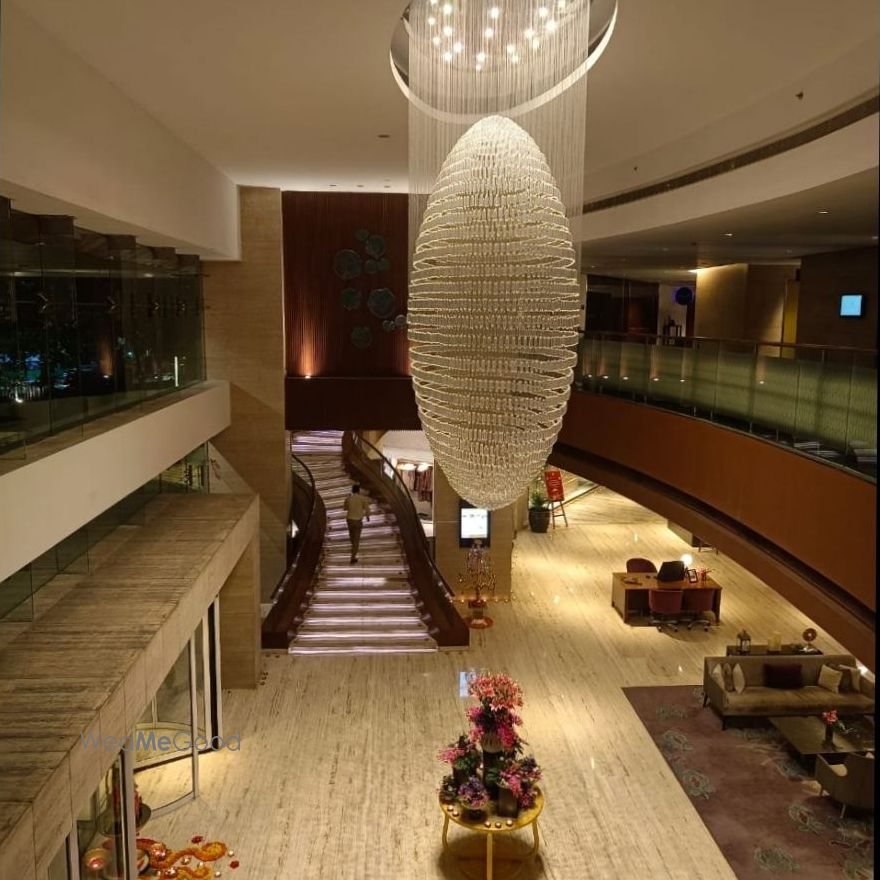 The atrium at Taj Yeshwantpur — a large woven ellipsoid chandelier hanging above a curved marble staircase, with the lobby gallery running around it