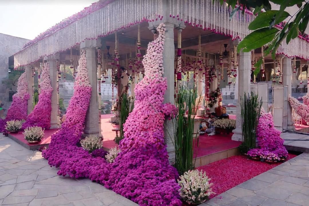 Ombré pink-to-magenta marigold floral pillars cascading over the Amita Rasa stone mandap, in-house decor by Panigrahana