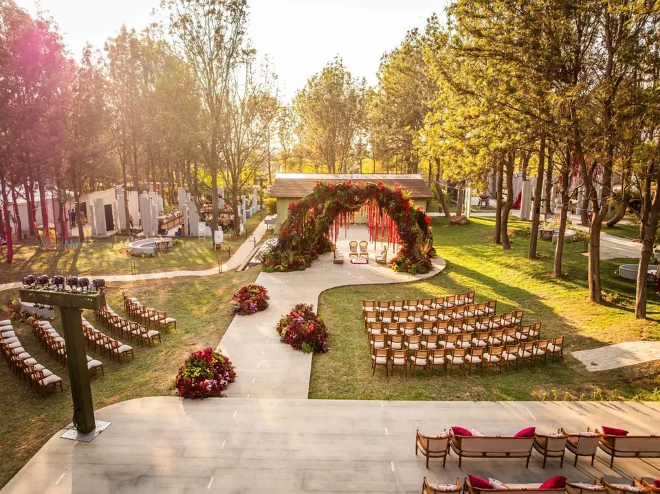 A wedding mandap and guest seating on the tree-lined Aakasam lawn at ORO