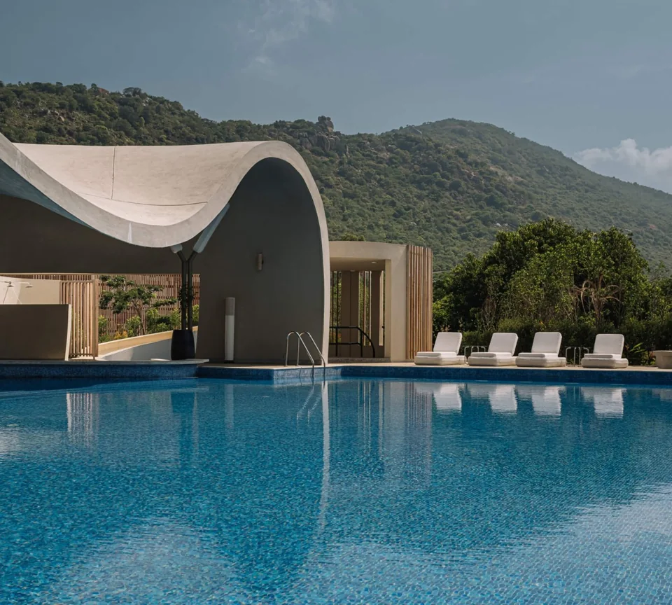 Infinity pool and white curved pavilion at ORO with Nandi Hills behind
