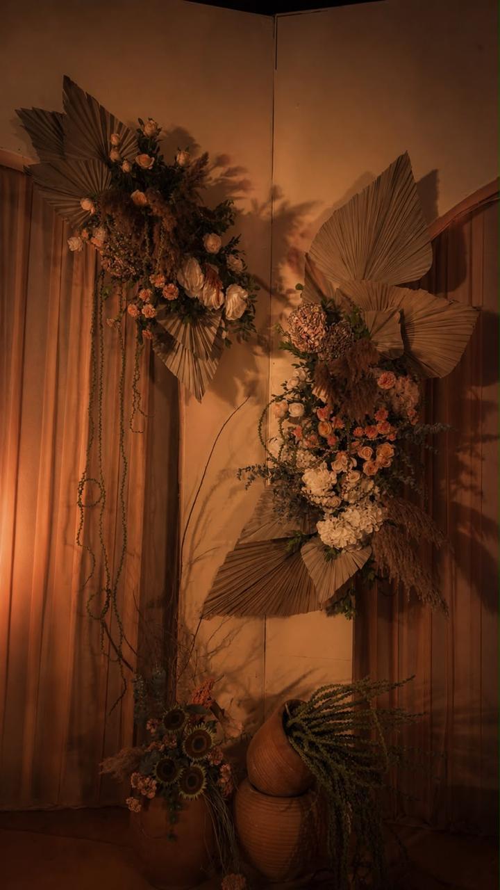 Dried palm and pastel floral installations on curtain backdrop at a boho wedding reception at Ramada Yelahanka Bangalore