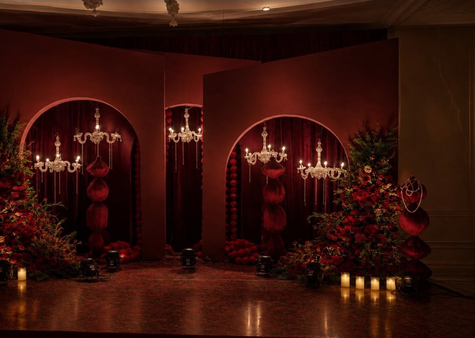Red velvet three-arch reception stage with crystal chandeliers at The Leela Palace Bengaluru
