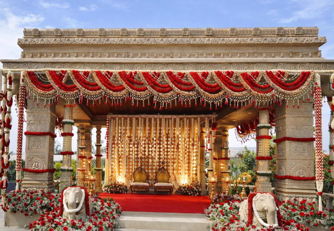 Carved stone temple mandap dressed in red rose swags and jasmine garlands with stone elephants at Utsavaa, Electronic City Bangalore