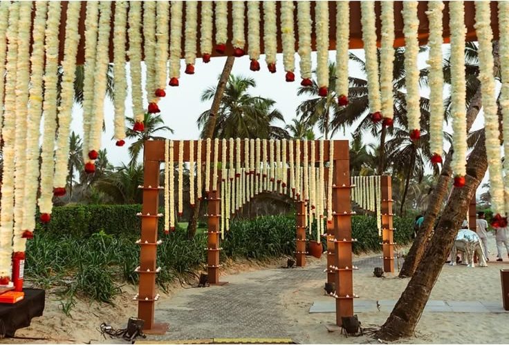 Corridor of hanging jasmine garlands on timber frames leading guests down to the beach ceremony