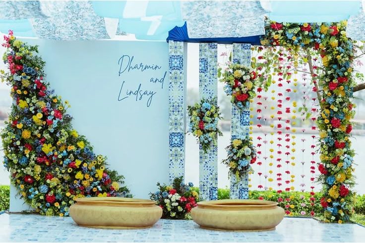 Haldi backdrop in blue and white Portuguese tile pattern with a cascade of mixed florals and gold urulis