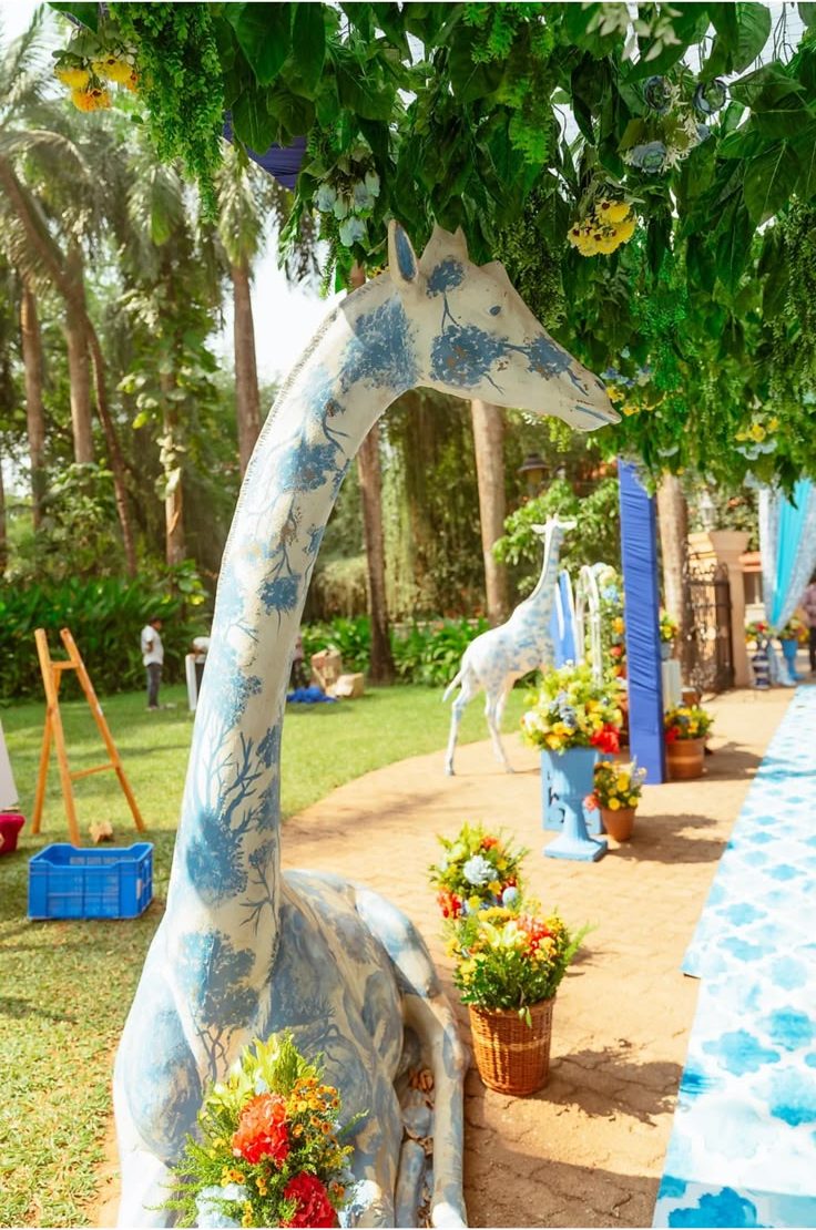 Hand-painted blue and white giraffe sculpture along the haldi walkway with a watercolour tile floor runner