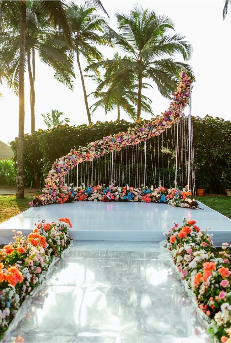 American ceremony set with a sweeping pastel floral arc, hanging crystal strands and a mirrored aisle at The St. Regis Goa