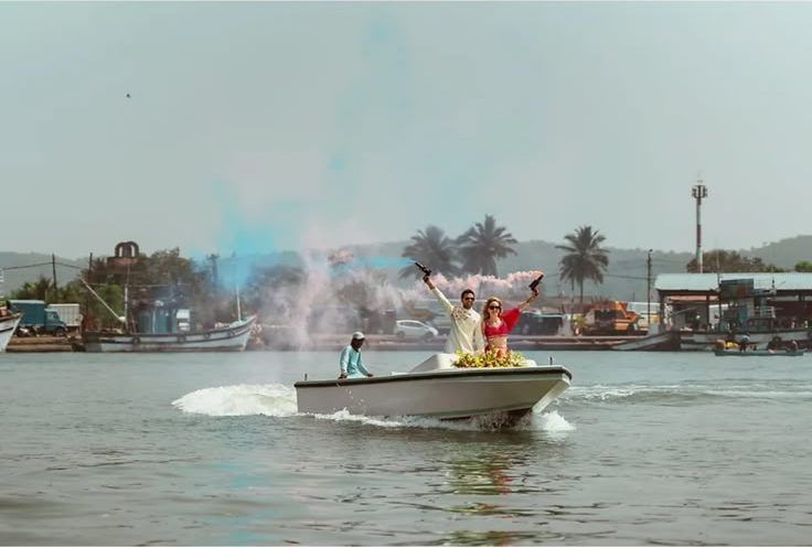 The couple arriving by speedboat with coloured smoke flares on the water in Goa